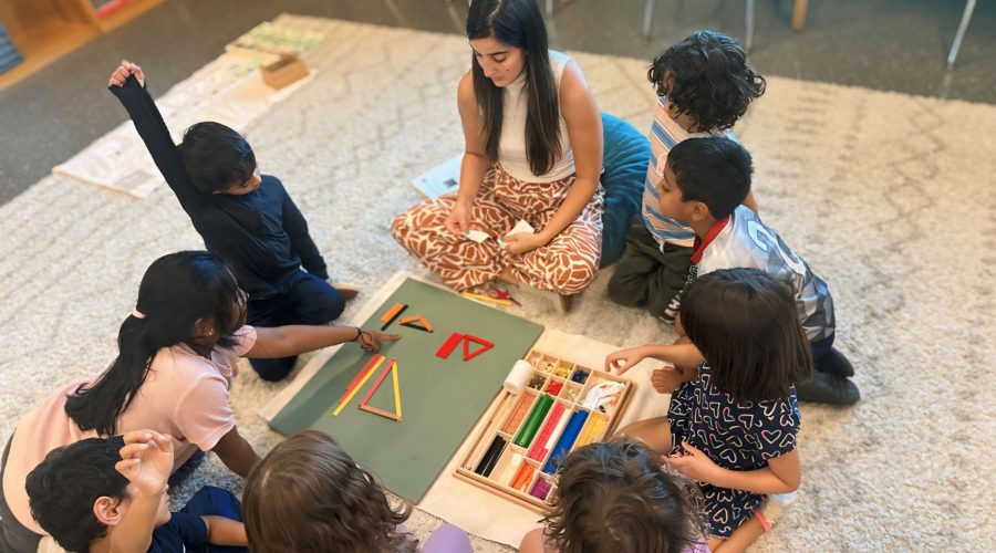 Students and teacher sitting on floor in Montessori Classroom doing thier lesson.